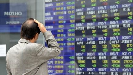 Un tokyoïte devant un tableau de changes. (AFP PHOTO / Yoshikazu TSUNO)