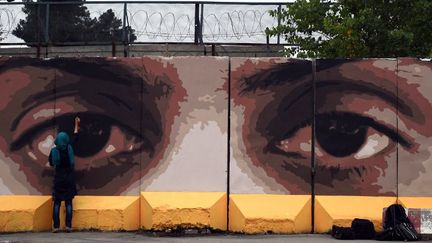 Maryam, une street artist kaboulie, peint des yeux géants sur un mur de Kaboul, pour dénoncer la corruption en Afhanistan.
 (WAKIL KOHSAR / AFP)