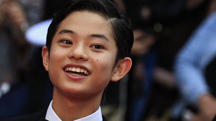 C'est une grande première à Cannes pour Soya Kurokawa, jeune acteur de 14 ans. Le Japonais, tout sourire au moment de monter les marches, est à l'affiche de "Monster", le film de Kore-Eda, premier long-métrage à être projeté en compétition pour ce 76e Festival de Cannes. (VALERY HACHE / AFP)