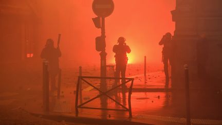 Un policier fait face à un incendie déclenché en plein cœur de Paris lors de la manifestation des "giles jaunes", samedi 1er décembre 2018. (LUCAS BARIOULET / AFP)