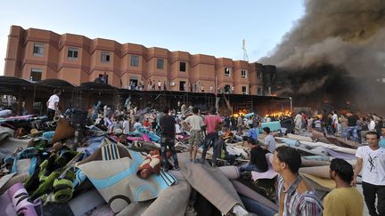 Des vendeurs de tapis regardent leur usine ravag&eacute;e par un incendie &agrave; Benghazi (Libye), le 15 octobre 2013. Ces derniers ont toutefois eu le temps d'extraire une partie de la marchandise. (ESAM AL-FETORI / REUTERS)