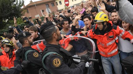 Des pompiers catalans forment un cordon de sécurité entre les manifestants indépendantistes et la police, à Sant Julia de Ramis (Espagne), le 1er octobre 2017. (LLUIS GENE / AFP)