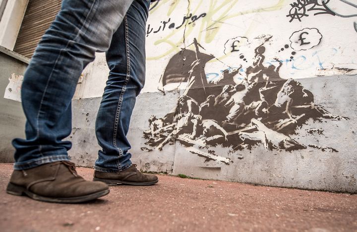 Un pochoir réalisé par l'artiste Banksy détourne "Le Radeau de la Méduse", de Géricault, sur un mur de Calais, le 12 décembre 2015.&nbsp; (PHILIPPE HUGUEN / AFP)