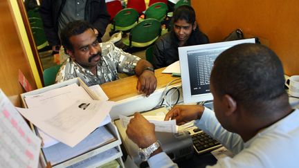 Des ressortissants sri-lankais en train de remplir leur dossier de demande de titre de séjour avec un employé de la préfecture de Paris, le 21 septembre 2007. (THOMAS COEX / AFP)