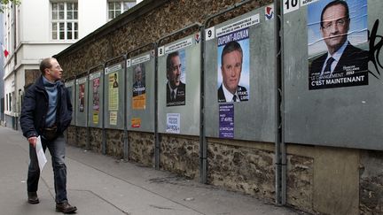 Un passant observe les panneaux &eacute;lectoraux o&ugrave; les affiches officielles des dix candidats &agrave; la pr&eacute;sidentielle 2012 ont &eacute;t&eacute; placard&eacute;es, le 9 avril 2012, &agrave; Paris. (THOMAS COEX / AFP)