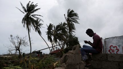 Un homme consulte son téléphone portable au milieu des ruines de sa maison détruite par l'ouragan Matthew, aux Cayes (Haïti), le 5 octobre 2016. (ANDRES MARTINEZ CASARES / REUTERS)