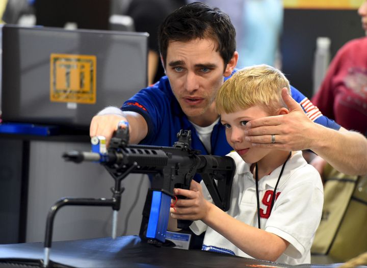 Brett Throckmorton, de l'entreprise de commerce d'armes Barnes Bullets, montre à un enfant comment regarder dans le viseur d'une arme automatique lors d'un rassemblement des sympathisants de la NRA à Nashville, dans le Tennessee, le 11 avril 2015. (Harrison McClary / Reuters)