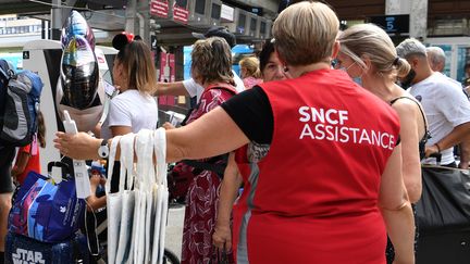 Un employé de la SNCF guide des passagers à la Gare de Lyon, à Paris, le 29 juillet 2022. (BERTRAND GUAY / AFP)