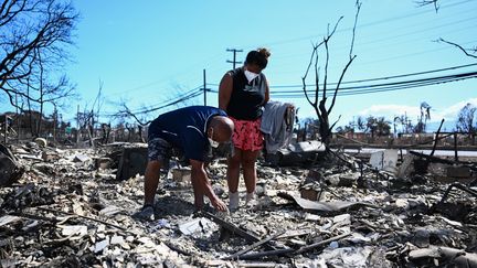 Deux habitants de l'île de Maui (Hawaï) cherchent leurs effets personnels dans leur maison familiale, après l'incendie qui a touché la ville de Lahaina, le 11 août 2023. (PATRICK T. FALLON / AFP)