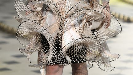 Chez Iris Van Herpen, les robes sont des enveloppes organiques: elles sont tantôt semblables à des chrysalides, deviennent parfois légères comme des papillons. Elles évoquent aussi des fossiles, des fleurs ou des créatures marines. La créatrice néerlandaise, toujours en quête d'expérimentations, navigue entre le monde animal et minéral. Faite de gouttes de verre et silicone transparent, une robe semble s'être cristallisée sur un mannequin.
 (Bertrand Guay/AFP)