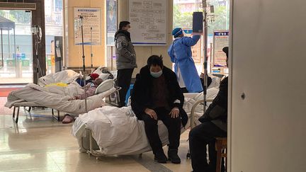 Un patient atteint du Covid-19 assis sur un lit d'un hôpital de Chongqing, le 23 décembre 2022. (NOEL CELIS / AFP)