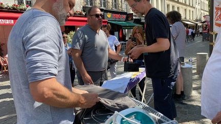 Des hommes s’essaient au repassage dans les rues du 4 ème arrondissement de Paris, le 3 juin 2023. (BORIS LOUMAGNE / RADIOFRANCE)