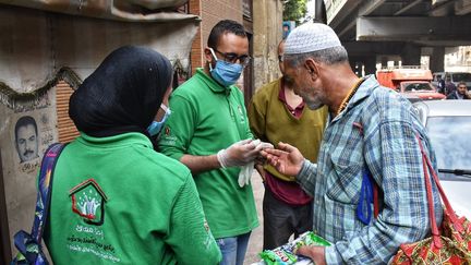 Des membres d'une association distribue, le 9 avril, du désinfectant à un SDF, en Egypte, l'un des pays africains le plus touché par le coronavirus. (ZIAD AHMED / NURPHOTO / AFP)