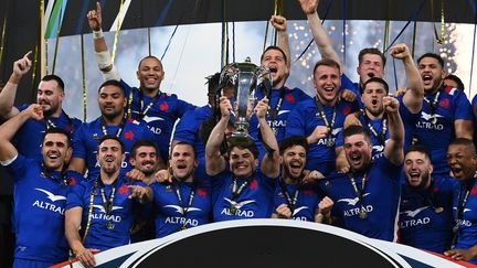 L'équipe de France autour de son capitaine Antoine Dupont qui soulève le trophée du Tournoi des six nations, après avoir réalisé le Grand Chelem le 19 mars 2022. (FRANCK FIFE / AFP)