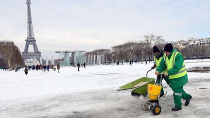 Des employ&eacute;s municipaux r&eacute;pandent du sel sur le Champ de Mars &agrave; Paris, le 13 mars 2013. (THOMAS SAMSON / AFP)