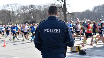 Un policier surveille le semi-marathon de Berlin (Allemagne), le 8 avril 2018. (PAUL ZINKEN / DPA / AFP)