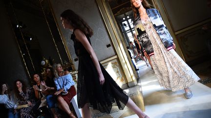 Le succès de Giambattista Valli dans le prêt-à-porter doit beaucoup à son triomphe dans la haute couture, qui a fait de ce Romain basé à Paris, l'enfant chéri de la jet set. Ce couturier a bâti son succès sur une ligne de vêtements uniques, spectaculaires, sophistiqués, qui ont su émouvoir la chanteuse Rihanna, l'actrice Emma Stone ou Amal Clooney.  Giambattista Valli est aussi crédité pour avoir contribué à faire de la haute couture un univers moins distant de la culture populaire contemporaine. "J'ai le problème exactement contraire de quelqu'un en panne d'inspiration, mon problème c'est d'avoir trop d'idées", a-t-il confié à Milan où il a présenté sa collection "Giamba". Le défilé a eu lieu sur fond d'une musique créée par Soko, muse et amie de Giambattista Valli. Il a expliqué avoir imaginé l'histoire d'une jeune femme rentrant chez elle après un séjour à Los Angeles aux Etats-Unis.  Après une nuit de fête avec ses anciens amis, elle s'effondre toute habillée pour se réveiller à 03H du matin, sous l'effet du décalage horaire. Elle met un peu de musique et commence à déambuler dans le palais. C'est ce moment particulier qu'il dit avoir voulu instiller dans son dernier défilé.
 (GIUSEPPE CACACE / AFP)