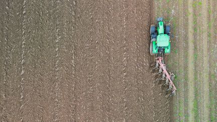 Un tracteur laboure un champ, à Tinteniac (Ille-et-Vilaine), le 24 novembre 2023. (DAMIEN MEYER / AFP)