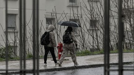 Deux piétons sous les trombes d'eau au cours d'un orage à Lyon, le 1er avril 2023. (MAXIME JEGAT / MAXPPP)