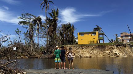 Des personnes regardent les dégâts causés par l'ouragan Maria à Porto Rico, le 6 octobre 2017. (RICARDO ARDUENGO / AFP)