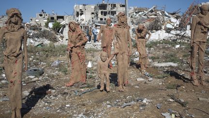 Certanes des statues en argile de Iyad Sabbah  sont couvertes de tâches rouges.
 (MAHMUD HAMS / AFP)