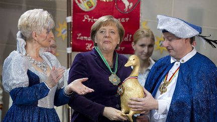 La Chanceli&egrave;re allemande Angela Merkel re&ccedil;oit en cadeau une oie en or lors d'une r&eacute;ception en compagnie de carnavaliers &agrave; Berlin, le 24 janvier 2012. (THOMAS PETER / REUTERS)