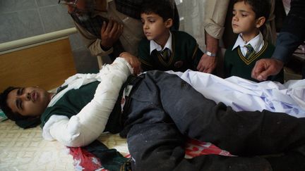 Un &eacute;tudiant bless&eacute;, entour&eacute; de deux jeunes &eacute;l&egrave;ves, dans un h&ocirc;pital de&nbsp;Peshawar (Pakistan), le 16 d&eacute;cembre 2014.&nbsp; (A MAJEED / AFP)