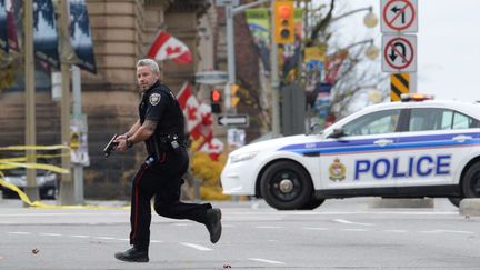 Un policier canadien accourt pr&egrave;s du Parlement &agrave; Ottawa (Canada), o&ugrave; a lieu une fusillade, le 22 octobre 2014. (SEAN KILPATRICK/AP/SIPA / AP)