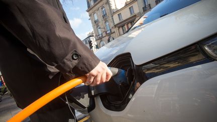 Un homme recharge une voiture électrique sur une borne à Bordeaux. Le montant de la prime offerte aux acheteurs de véhicules électriques neufs a augmenté le 1er juin 2020. (SIPA)