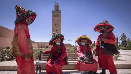 Des vendeurs d'eau marocains, impactés par la crise du Covid-19&nbsp;à cause de la rareté des touristes, devant la mosquée de la Koutoubia dans la ville de Marrakech, le 6 mai 2021.&nbsp; (FADEL SENNA / AFP)