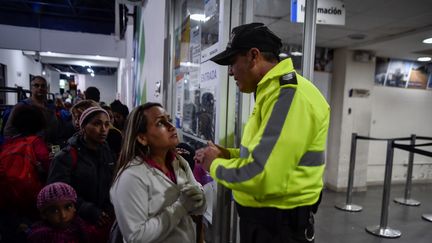 Un policier équatorien explique la procédure d'admission en Equateur, devant le bureau de l'immigration, à Tulcan (Equateur), le 19 août 2018. (LUIS ROBAYO / AFP)