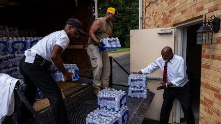 Des membres d'une paroisse baptiste de Jackson livrent des packs d'eau lors de la messe du dimanche matin, le 4 septembre 2022. (SETH HERALD / AFP)