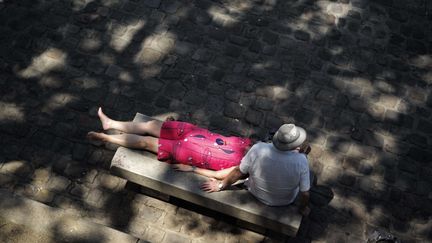 Un couple se prélasse sur un banc&nbsp;alors que la canicule sévit à Paris, le 26 juin 2019. (KAMIL ZIHNIOGLU / AP / SIPA / AP)