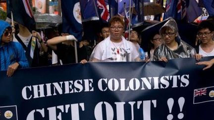 Hong Kong, le 1er juillet 2013. Le ralliement pour la démocratie défile avec des drapeaux britanniques et une bannière qui annonce la couleur: «Colons chinois, dehors»... (AFP PHOTO / ALEX OGLE)