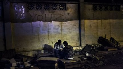 dans la pénombre, ces deux jeunes jouent aux dominos parmi les déchets du marché voisin. C'est l'envie de se couper, d’être tranquille, qui les a poussés ici. (Romain Laurendeau)