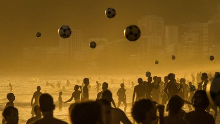 Des Br&eacute;siliens jouent au football sur la plage d'Ipanema au coucher du soleil &agrave; Rio de Janeiro (Br&eacute;sil), le 9 janvier 2014. (YASUYOSHI CHIBA / AFP)