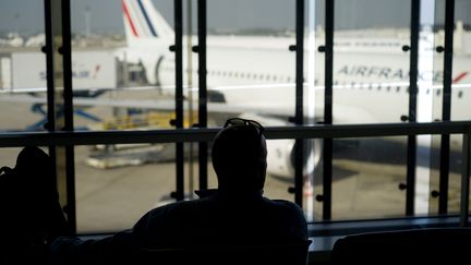 Un passager de dos contemple un avion de la compagnie Air France, le 15 septembre 2014. (Photo d'illustration) (KENZO TRIBOUILLARD / AFP)