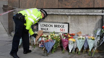 Un&nbsp;policier britannique dépose une gerbe de fleurs sur le London Bridge, dimanche 1er décembre, après l'attaque qui a fait deux morts.
 (TOBY MELVILLE / REUTERS)