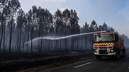 Des pompiers arrosent une zone brûlée, le 14 septembre 2022 à Saumos (Gironde). (THIBAUD MORITZ / AFP)