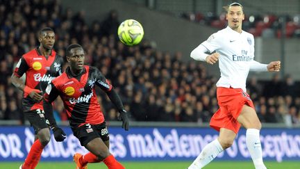 Le d&eacute;fenseur de Guingamp Benjamin Angoua et le l'attaquant Zlatan Ibrahimovic, le 14 d&eacute;cembre 2014, dans le stade du Roudourou. (FRED TANNEAU / AFP)