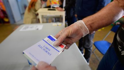 Un assesseur présente une carte électorale dans un bureau de vote. Illustration.&nbsp; (RICHARD BRUNEL / MAXPPP)