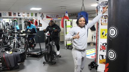 Trois des athlètes étrangers bénéficiaires de la bourse Solidarité olympique s'entraînent dans la salle de préparation physique, le 22 janvier 2024, au CRJS de Petit-Couronne (Seine-Maritime). 
Au premier plan, Resquin Mongondo, judoka centrafricain, au centre le judoka tanzanien Andrew Mlugu et au fond, le judoka nigérian Ismael Alhassane. (APOLLINE MERLE / FRANCEINFO SPORT)