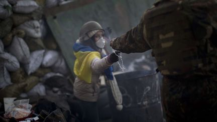 Un manifestant tend &agrave; une camarade un chapelet sur une barricade &agrave; Kiev (Ukraine), le 31 janvier 2014. (EMILIO MORENATTI / AP / SIPA)