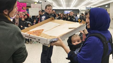 Une femme offre une pizza à des manifestants opposés au décret anti-immigration, à l'aéroport Dulles de Washington, samedi 28 janvier 2017. (REUTERS STAFF / REUTERS)