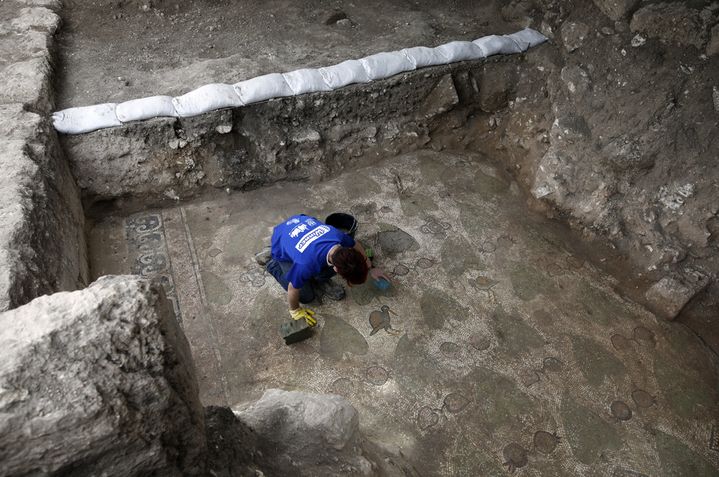 Un volontaire des Antiquités israéliennes travaille sur une mosaïque au sol du monastère byzantin antique (20 décembre 2017)
 (Menahem Kahana / AFP)