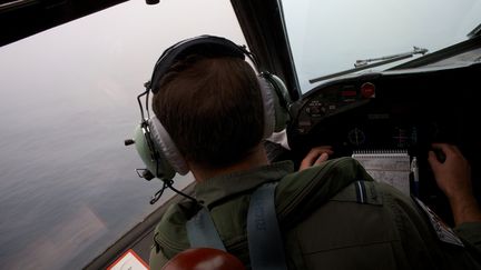 Un officier australien survole l'oc&eacute;an Indien, le 24 mars 2014, &agrave; la recherche de d&eacute;bris du Boeing disparu de la Malaysia Airlines. (RICHARD WAINWRIGHT / AFP)