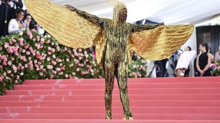 Une fois sur les marches du Met, Billy Porter n'a pas hésité à dévoiler l'ensemble de sa tenue face aux photographes. Du doré, et rien que du doré, de la tête aux pieds.&nbsp; (CHARLES SYKES / AP / SIPA)