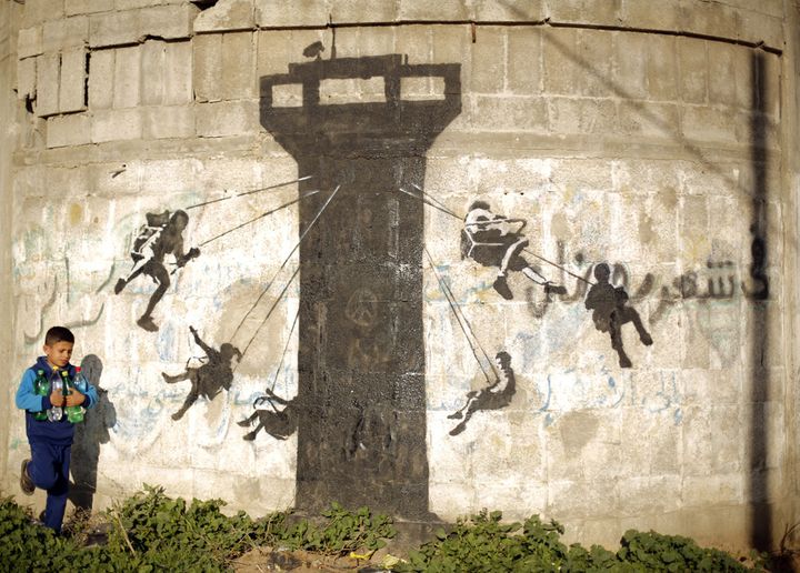 Un enfant près d'une fresque représentant un mirador de l'armée israélienne transformé en manège (27 février 2015)
 (Mohammed Abed / AFP)