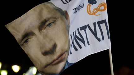 Portrait de Vladimir Poutine sur un drapeau &agrave; Moscou (Russie), le 4 mars 2012. (JOHN MACDOUGALL / AFP)