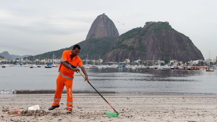 Un employ&eacute; nettoie la plage de Botafogo, &agrave; Rio (Br&eacute;sil), le 10 mars 2015.&nbsp; (CHINE NOUVELLE / XINHUA / SIPA )